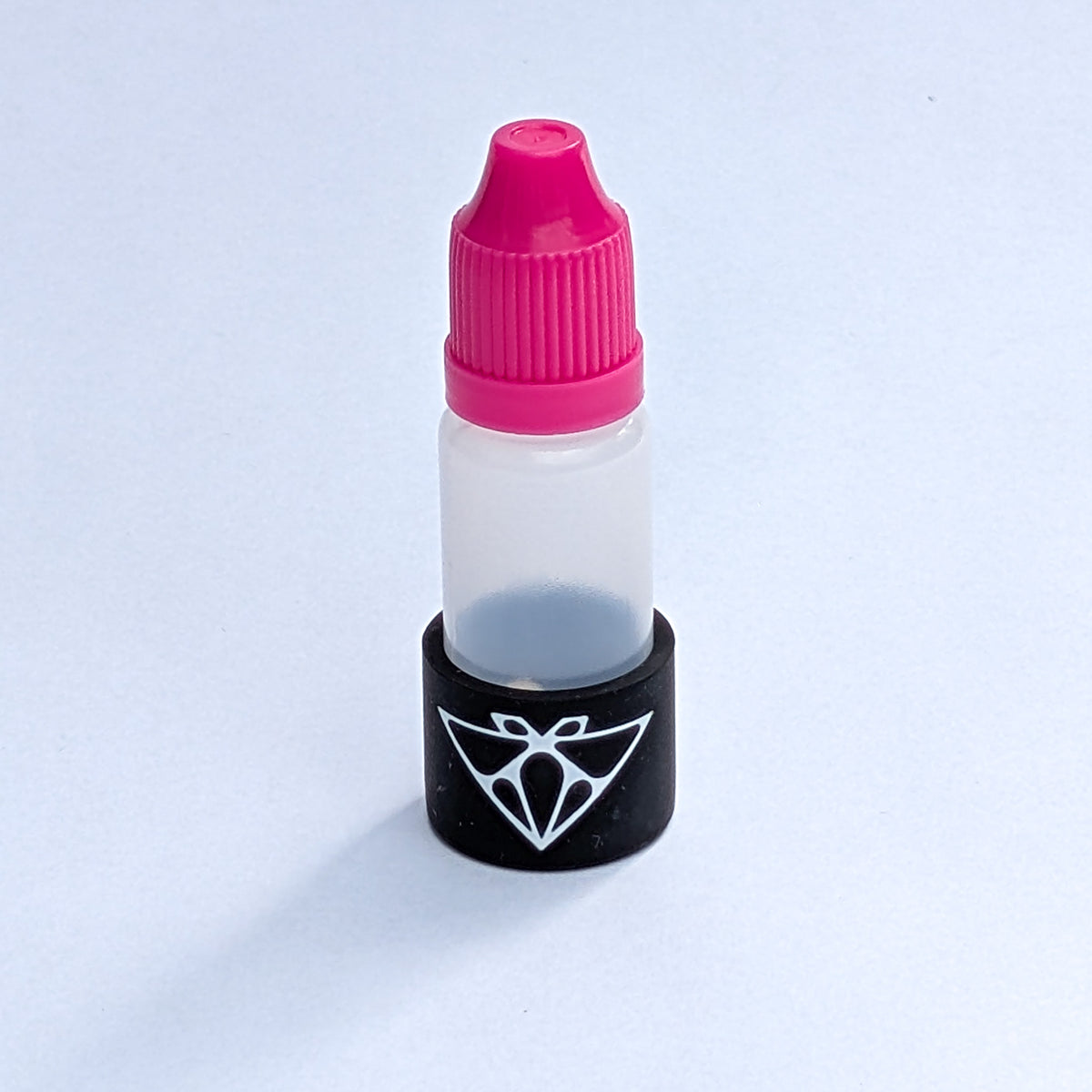 Single magnetic glue bottle close-up, pink cap and black base with the Moth logo