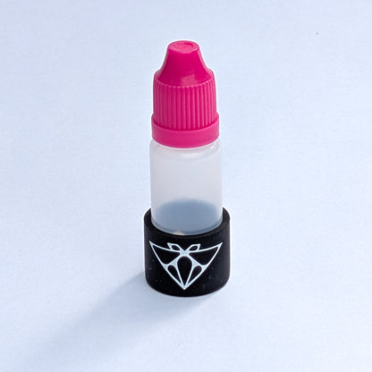 Single magnetic glue bottle close-up, pink cap and black base with the Moth logo