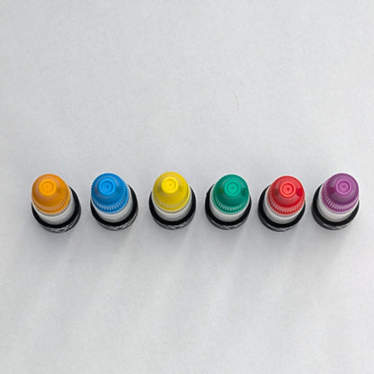 Six magnetic glue bottles from above, showing the coloured cap tops in a row
