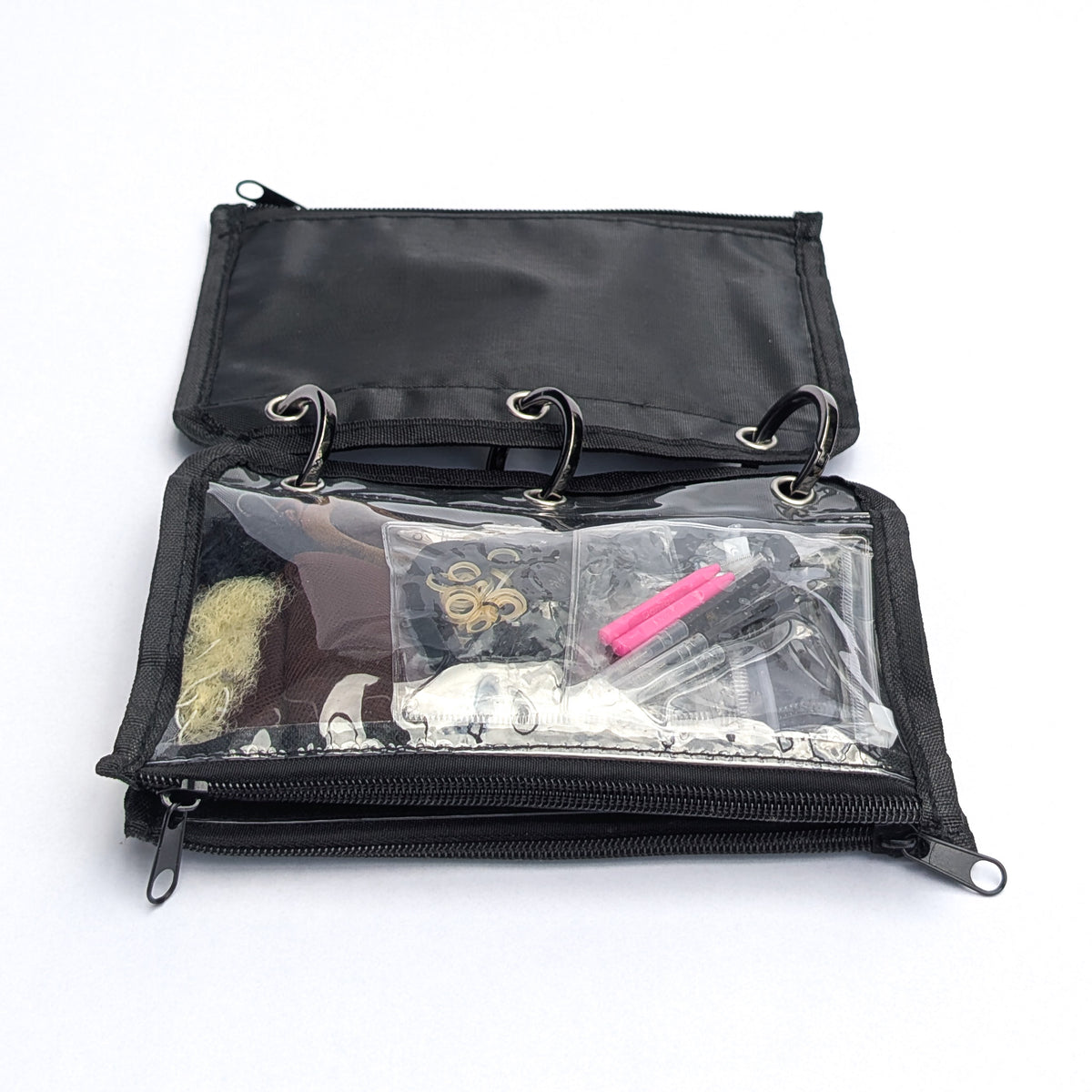 A black zippered ring-binder style pouch shown open on a white background, with clear front pockets containing small accessories and tools.