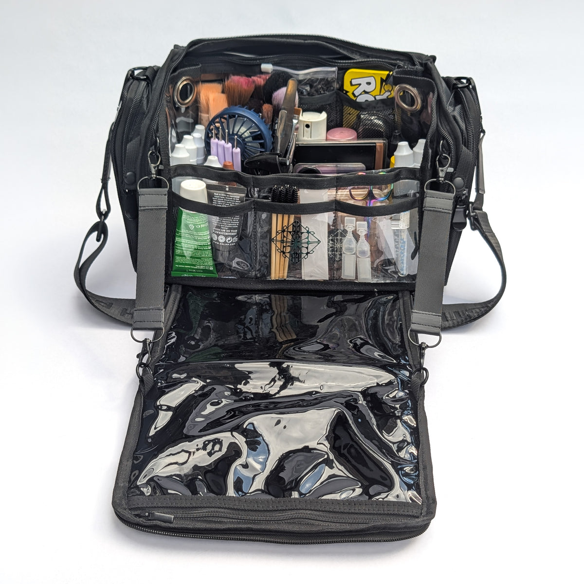 Moth Pro set bag with cosmetics and accessories, photographed on a clean white studio background. The bag has multiple compartments, mesh pockets, and a glossy black interior lining.
