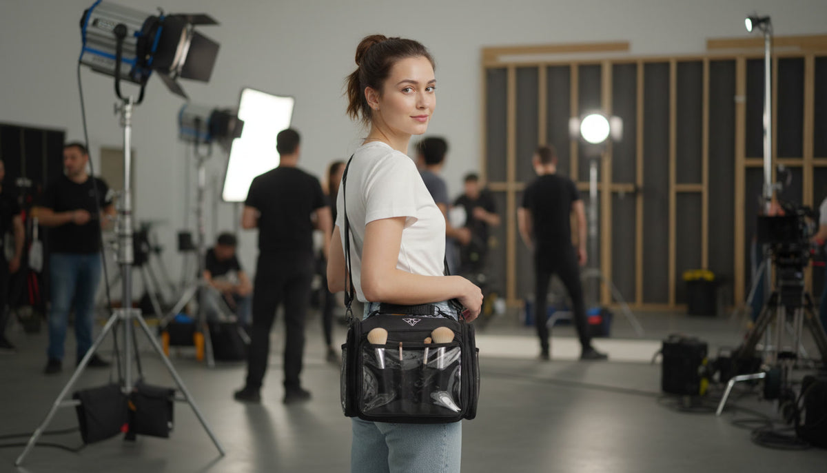A woman in a white t-shirt and jeans stands in a photography studio wearing the moth pro bag over her shoulder with a clear front pocket and a small circular cutout.